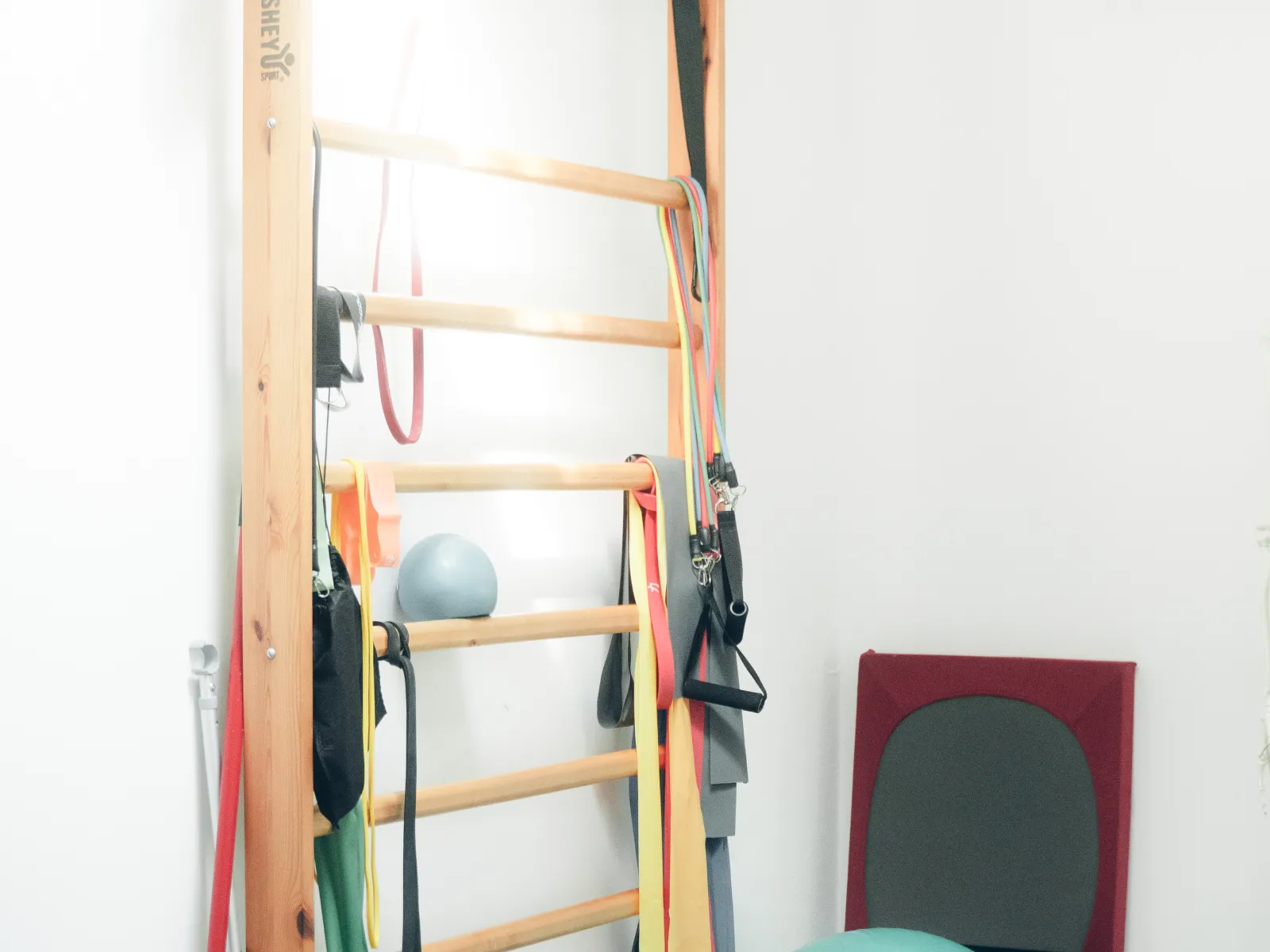 Sprossenwand mit Therabändern im Übungsraum der Praxis Schweitzer